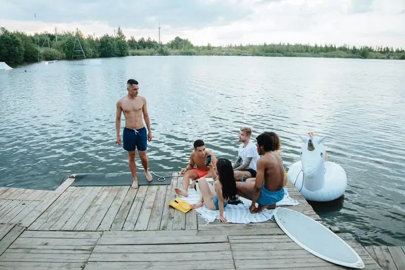 a group of people sitting on a dock by a body of water