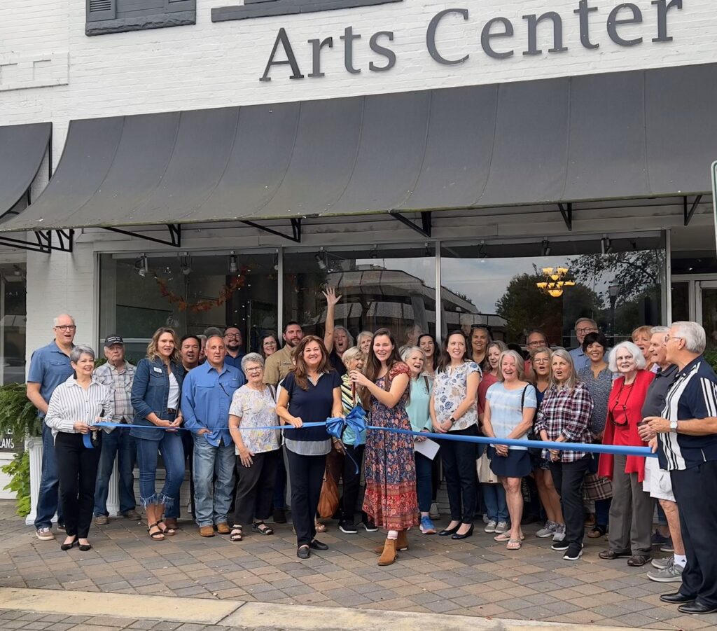 Grand Opening of The Arts Center of Hartwell. Large group of people standing in front of Arts Center building behind ribbon before cutting. Smiling.